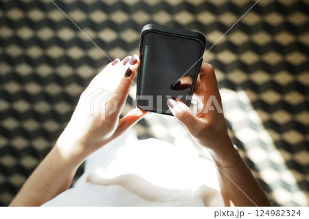 Hands Holding Smartphone with Blank Screen Above Pattern 124982324