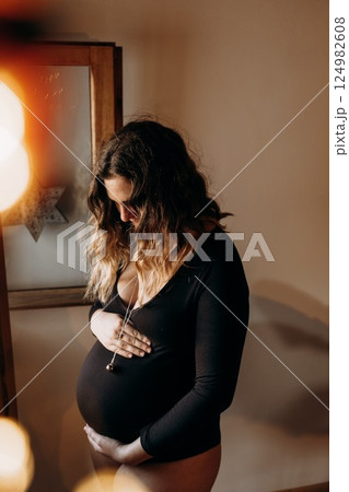 Pregnant Woman Cradling Belly in Peaceful Home Setting Pregnant Woman Cradling Belly in Peaceful Home Setting 124982608