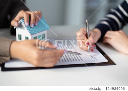 Real estate agent assisting clients with property contract signing. Real estate agent assisting clients with property contract signing. 124984006