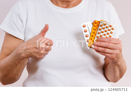 Elderly senior woman with tablets, vitamins or supplements in hand 124985711
