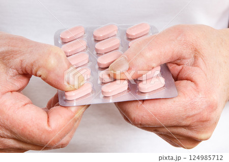 Elderly senior woman with tablets, vitamins or supplements in hand 124985712