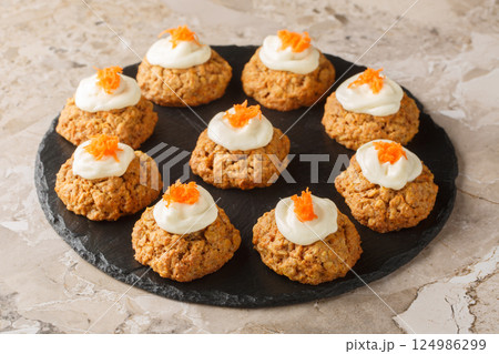 Soft crumbly carrot oatmeal cookie cake with cream cheese frosting close-up on plate. Horizontal 124986299