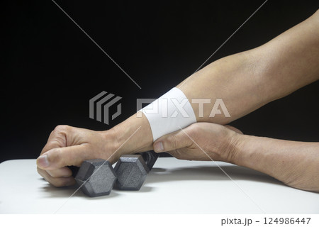 湿布を貼ってダンベルでリハビリをしている老人の腕 124986447