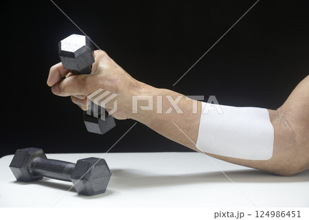 湿布を貼ってダンベルでリハビリをしている老人の腕 湿布を貼ってダンベルでリハビリをしている老人の腕 124986451