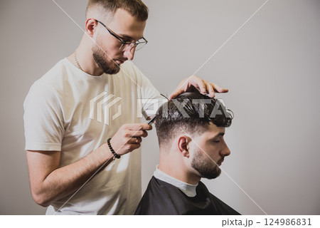 Young man with trendy haircut at barber shop. Young man with trendy haircut at barber shop. 124986831
