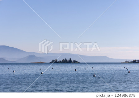 Peaceful spring morning on Lake Garda with distant San Biagio island 124986879