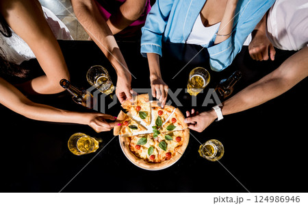 Cheerful friends in the pub. Drinking beer, eating pizza, talking, having fun. 124986946