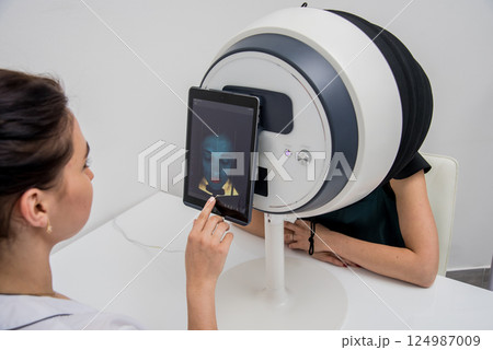 Face skin analyze system. Cosmetologist analyzing woman face. Face skin analyze system. Cosmetologist analyzing woman face. 124987009
