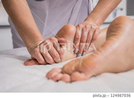 Beautiful young woman enjoying foot massage in spa salon. Cosmetology 124987036