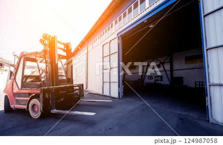 The big industrial forklift drives into the warehouse. The big industrial forklift drives into the warehouse. 124987058