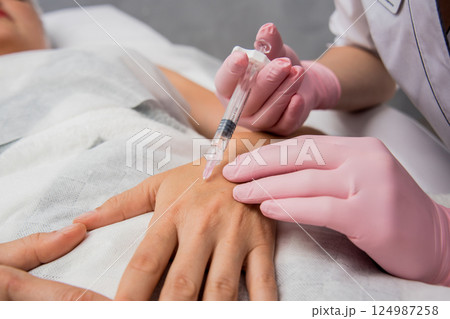 The doctor cosmetologist makes the arms injections procedure.  124987258