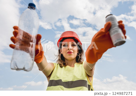 Woman volunteer helps clean the field of plastic garbage. 124987271
