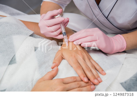 The doctor cosmetologist makes the arms injections procedure. The doctor cosmetologist makes the arms injections procedure. 124987318