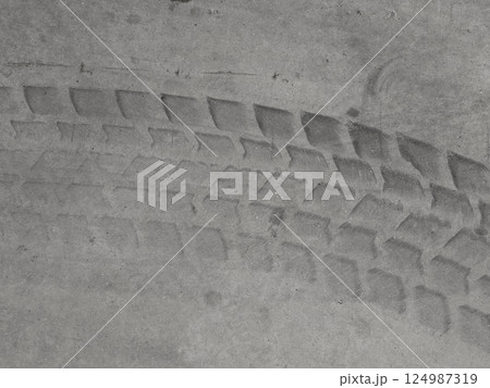 Black and white photography depicting a tire track imprinted on a rough concrete surface Black and white photography depicting a tire track imprinted on a rough concrete surface 124987319