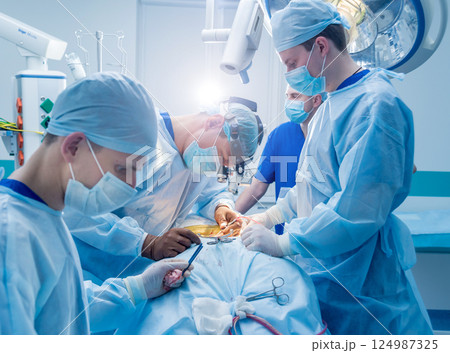 Spinal surgery. Group of surgeons in operating room with surgery equipment. 124987325
