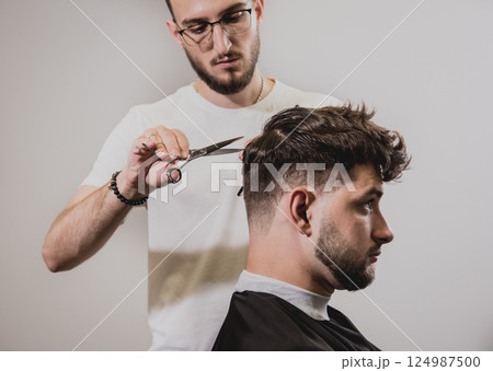 Young man with trendy haircut at barber shop.  124987500