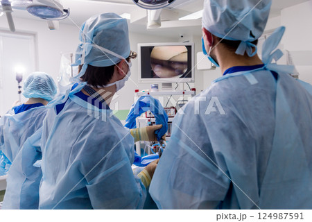 Arthroscope surgery. Orthopedic surgeons in teamwork in the operating room  124987591