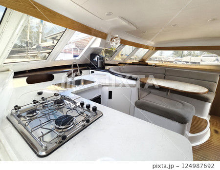 A cozy living room and kitchen featuring a stylish curved couch and a table located on sailing boat A cozy living room and kitchen featuring a stylish curved couch and a table located on sailing boat 124987692