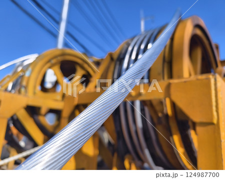 A large wooden spool of high-voltage electric wires is located on the road A large wooden spool of high-voltage electric wires is located on the road 124987700