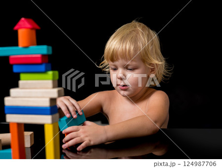 A child with an autism spectrum disorder builds a house from a wooden constructor. Concept of autism. A child with an autism spectrum disorder builds a house from a wooden constructor. Concept of autism. 124987706