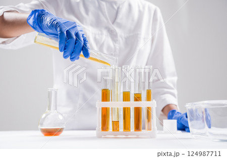 Scientist pouring organic oil. Beauty and cosmetics sciences. Scientist pouring organic oil. Beauty and cosmetics sciences. 124987711