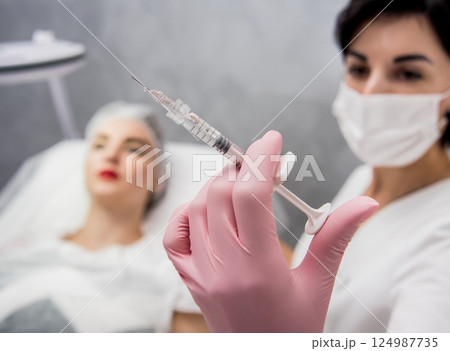 The doctor cosmetologist makes the facial injections procedure. The doctor cosmetologist makes the facial injections procedure. 124987735