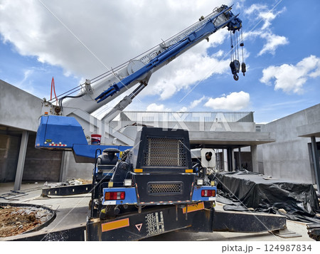 A large auto crane is parked right in front of a building that is currently under construction A large auto crane is parked right in front of a building that is currently under construction 124987834