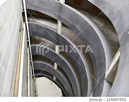 A spacious and modern parking garage with clean lines and abundant lighting. 124987858