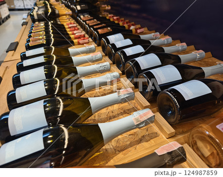 A variety of bottles of champagne are elegantly lined up on a wooden shelf 124987859