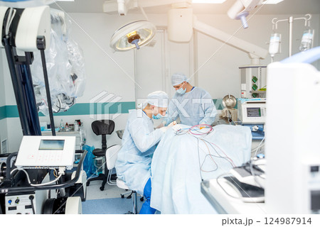 Brain surgery. Group of surgeons in operating room with surgery equipment. 124987914