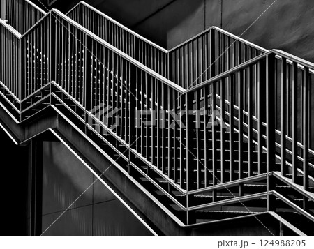 A set of stairs ascending a large black wall 124988205