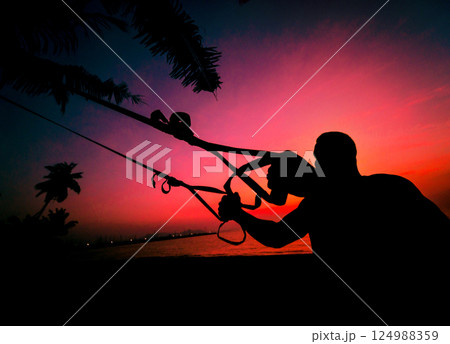The athlete performs exercises on the beach with fitness straps 124988359