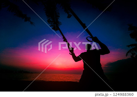 The athlete performs exercises on the beach with fitness straps 124988360
