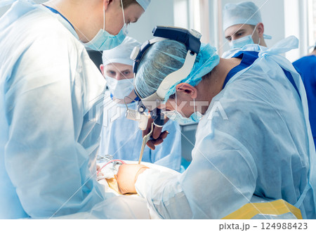 Spinal surgery. Group of surgeons in operating room with surgery equipment.  124988423