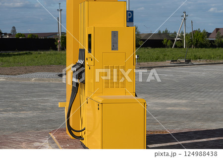 A bright yellow fuel dispenser stands alone at a gas station in a rural location, ready for vehicles to refuel A bright yellow fuel dispenser stands alone at a gas station in a rural location, ready for vehicles to refuel 124988438