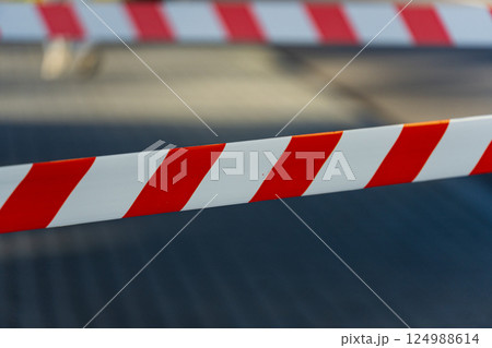Brightly colored barricade tape indicates a restricted area at a construction site in an urban environment under clear sky Brightly colored barricade tape indicates a restricted area at a construction site in an urban environment under clear sky 124988614