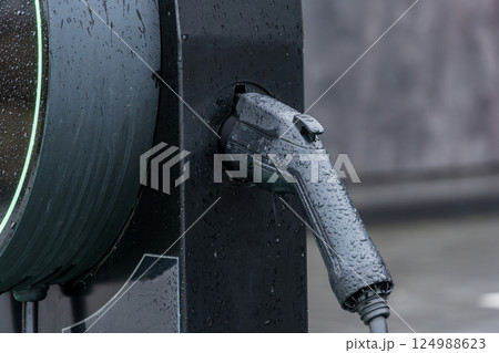 Water droplets cling to a charging gun as it fits into an electric vehicle's charging port at a modern station in the city Water droplets cling to a charging gun as it fits into an electric vehicle's charging port at a modern station in the city 124988623