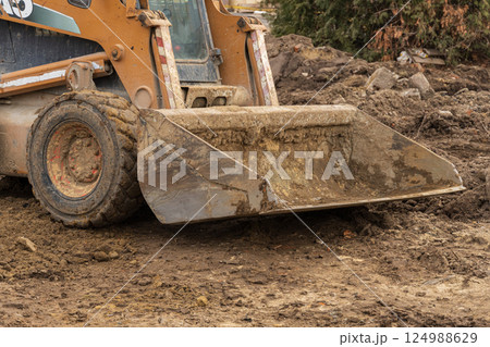 A construction vehicle is actively moving and leveling dirt at a site, contributing to the groundwork for future development A construction vehicle is actively moving and leveling dirt at a site, contributing to the groundwork for future development 124988629