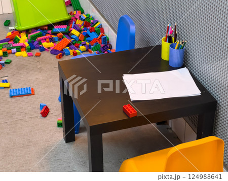 Children are engaged in creative play with colorful plastic building blocks around a small table in a cozy room 124988641