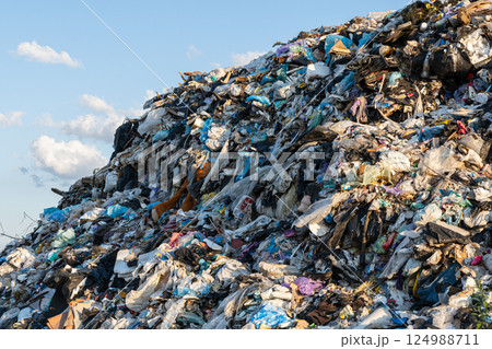 A vast heap of discarded plastic materials looms against the horizon, reflecting humanity's struggle with waste management and pollution 124988711