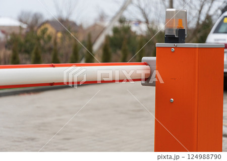 A security barrier stands at the entrance of a parking lot, ensuring controlled access to vehicles in a suburban neighborhood on a cloudy day A security barrier stands at the entrance of a parking lot, ensuring controlled access to vehicles in a suburban neighborhood on a cloudy day 124988790