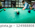 Young man trying to hit the ball in billiard. 124988808