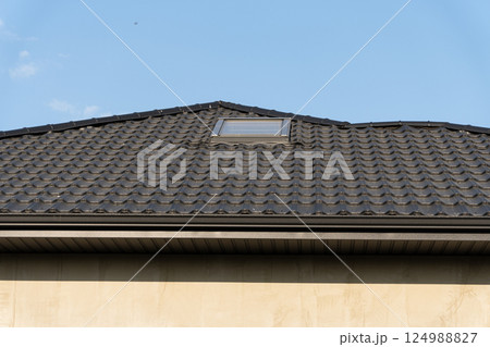 A residential building with a distinct rooftop design hosts a skylight, illuminated by the bright blue sky above 124988827