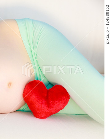Pregnant woman lying on couch showing naked belly Pregnant woman lying on couch showing naked belly 124989152