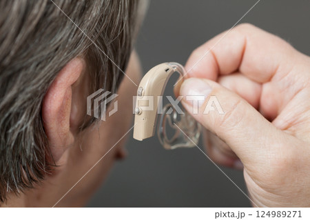 Closeup senior woman using hearing aid Closeup senior woman using hearing aid 124989271