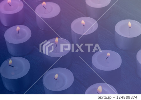 Tea light candles on a dark background, many lights in the dark Tea light candles on a dark background, many lights in the dark 124989874