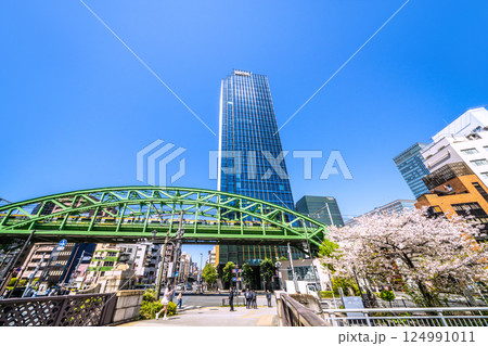 日本の東京都市景観　昌平橋交差点の上に架かる総武本線松住橋架道橋を走る総武線や超高層ビル、桜など 124991011