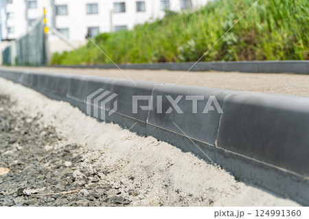 Construction of a pedestrian path. Paving of pedestrian paths on city streets. Road curbs and sidewalks. New curbs close up. Curbs detail. Soft focus 124991360