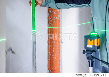 Construction worker using laser level and ruler taking measurements on site 124991714