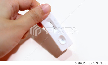 Hand holding a brand new blank self-test kit for Covid flu test. With copy space on the right. Hand holding a brand new blank self-test kit for Covid flu test. With copy space on the right. 124991950